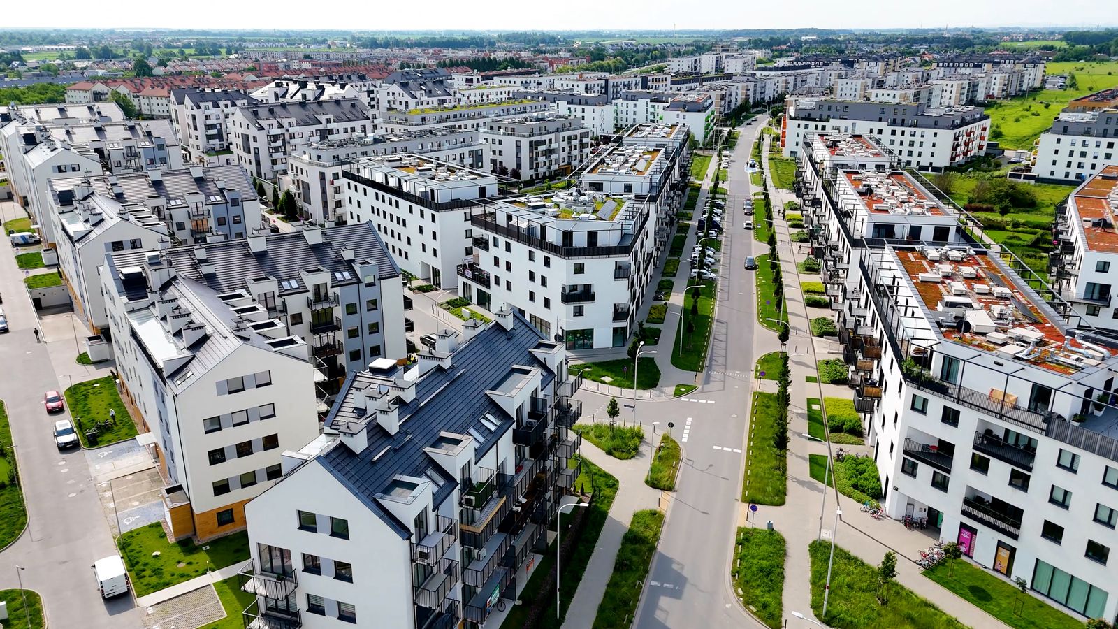 Luftaufnahme eines Wohnquartiers mit Stra&szlig;enzug, Gr&uuml;nfl&auml;chen und Dachterrassen