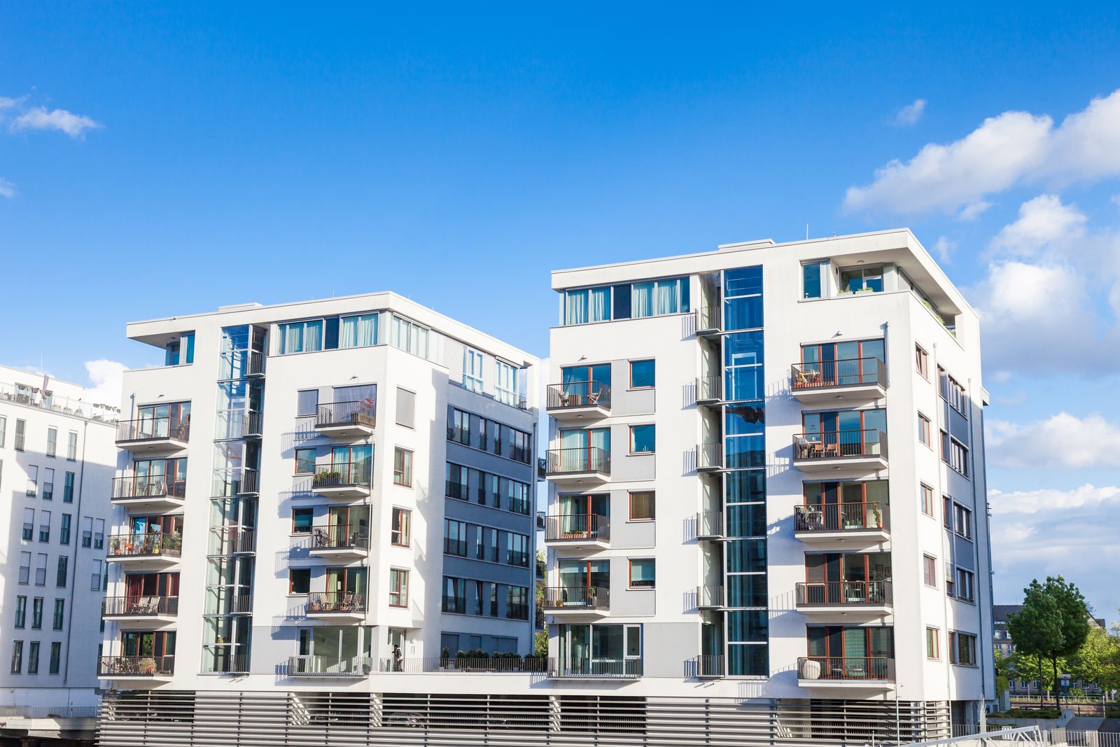 Zwei moderne Wohngeb&auml;ude mit klaren vertikalen Linien vor blauem Himmel